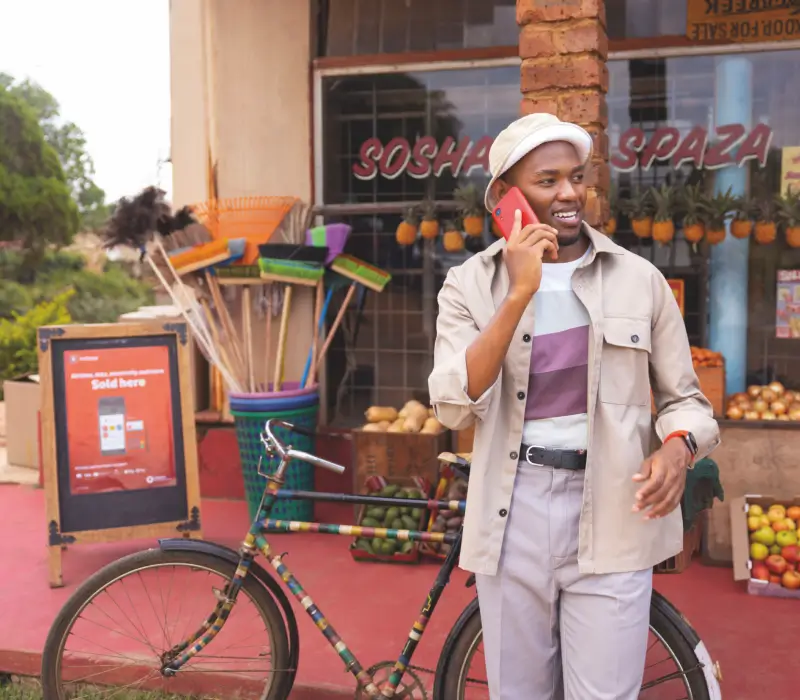 Person on phone leaning against bicycle